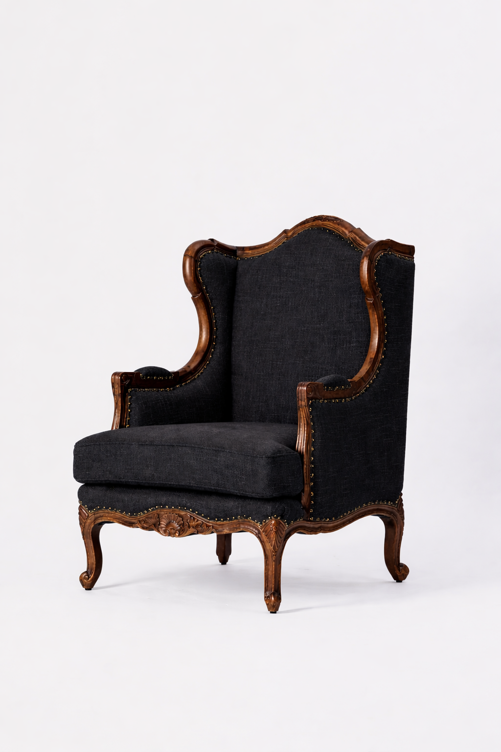The Montclair Heritage Wingback Armchair is a vintage, handcrafted solid wood chair with ornate carvings and dark upholstered cushions, shown against a plain white background.